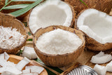 Coconut halves and pieces on a wooden surface with a grater.