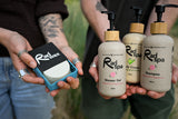 Three pump bottles of Rad spa body care products and a boxed rad wax bar are held in hands outdoors. The products include Shower Gel, Body Cream, and Shampoo, with beige bottles, black pumps, and light wood caps.